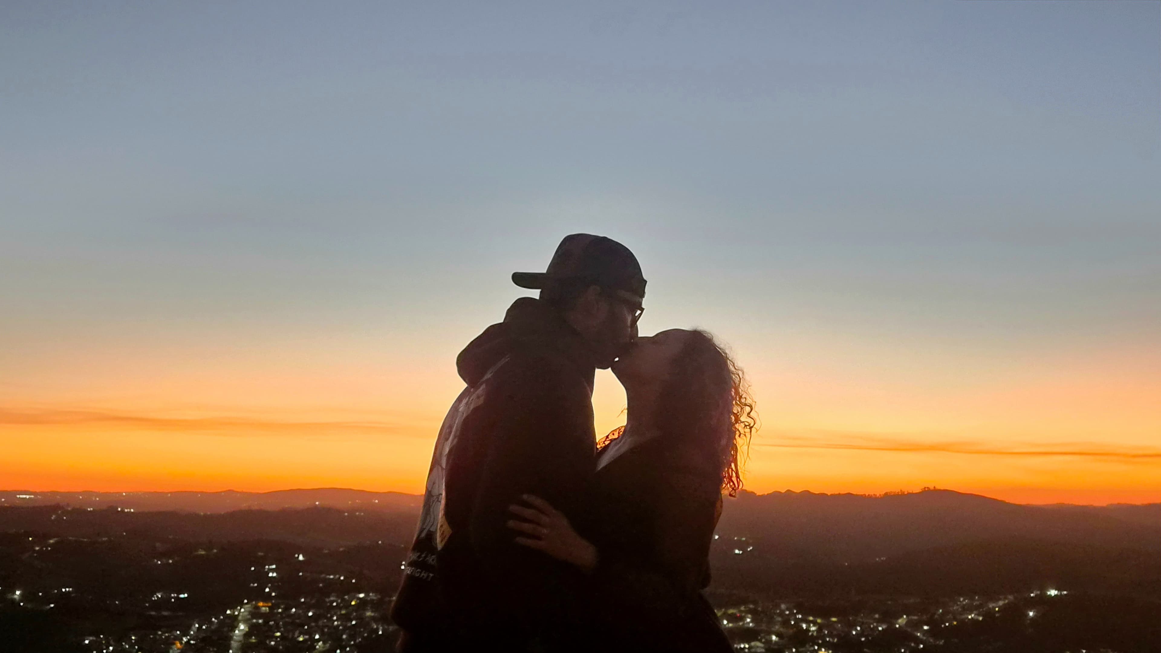 Jhenipher e Felipe abraçados contra o pôr do sol